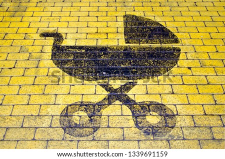 Baby buggy icon in black on yellow pavement indicating parking spot for visitors with small children