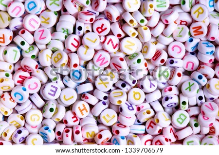 White beads with multicolored English letters close-up.