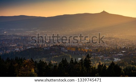 City under the ridge of mountains and mountains "Jested" illuminated by the rays of the setting sun.