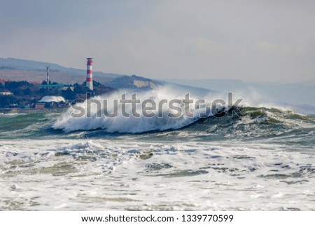 Beautiful and dangerous storm waves on the background of the Gelendzhik lighthouse. Resort Gelendzhik, Caucasus, steep rocky shore.