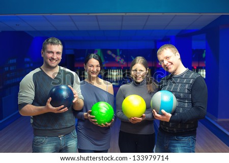 Group of four friends in a bowling alley having fun