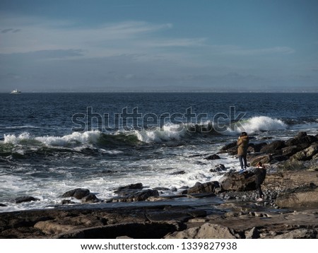 Woman taking picture of huge waves, west coast of Ireland. Atlantic ocean, Wild Atlantic way, Burren national geopark.