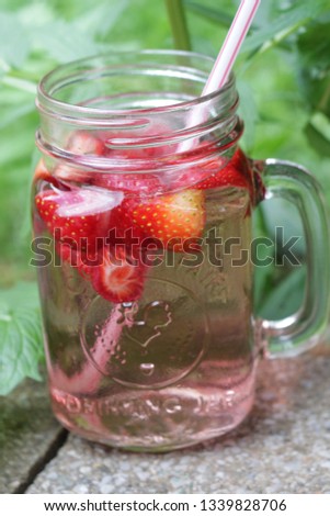 Refreshing summer drink with Strawberry and ice in a cute glass. Water, ice and strawberry. Grass background. - Image