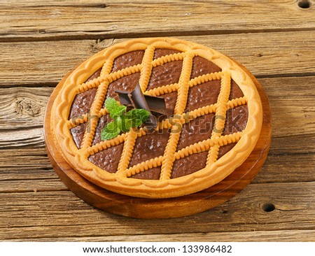 whole round chocolate tart on a wooden background