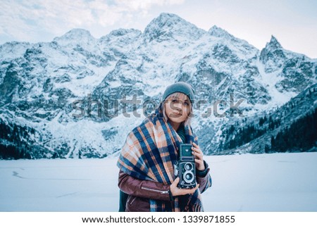 Beautiful girl makes a photo on an old vintage camera. In the mountains in winter, adventure and travel