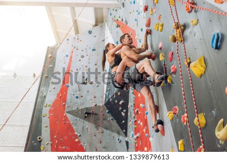 young fit man and woman have joined a climbing gym. low view. full length photo. speed freestyle