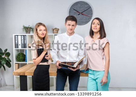 Theme business, teamwork and partnerships. A group of young people, three people, stand in an office near the table in official clothes, work with documents, make praks sign contracts.