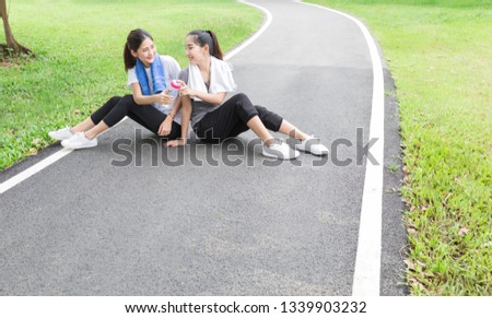 couple attractive asian female exercise and relax in public park, they drink clean water, they  feeling fresh and happy, health promotion activity