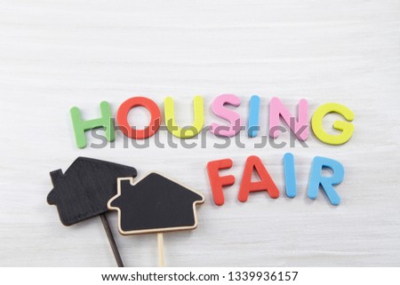 The word "housing fair" written in wooden colorful letters on white wooden background. Blank various blackboard labels. 