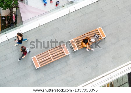 top aerial view fashion woman with shopping bag uses smartphone sit on wooden bench at walkway pedestrian with blur people are walking, , concept of social still life with technology and lifestyle Royalty-Free Stock Photo #1339953395