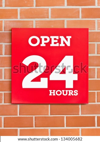 24 hours red signboard on brick background.