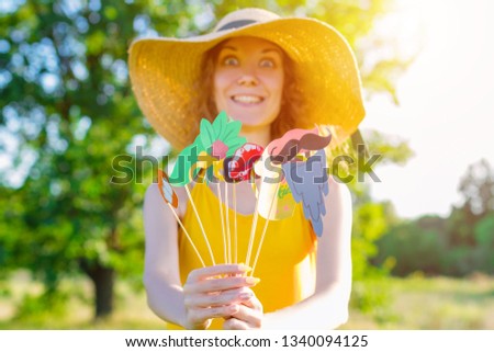 Happy beauty comic woman female wears yellow summer lite dress and summer hat enjoying sunny day outdoor in green park with colorful party props. Active funny outdoor leisure lifestyle concept.
