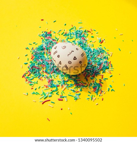 One Easter egg with memphis style print on yellow bright background with confetti.  Happy spring holidays concept. Minimal