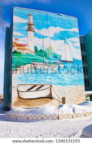 Beautiful painting of graffiti on the facade of a five-storey building in Russia. Winter. Drawing sea, lighthouse yacht, boat. RB