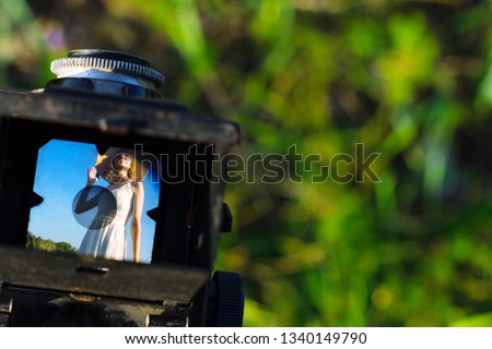 Take picture on old ancient rare retro film photo camera with two lenses of happy beautiful fun girl woman hipster wear long white dress on big large wide summer hot spring sunny green light field
