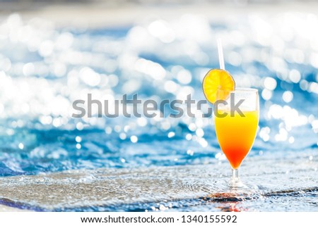 alcohol cocktail with a slice of an orange on the glass standing at the edge of a resort pool. Concept of luxury vacation. free space for advertising text Royalty-Free Stock Photo #1340155592