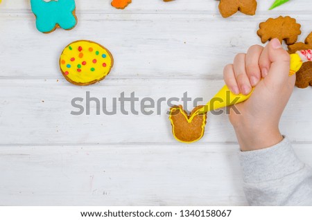 Child hands decorating honemade gingerbread with icing sugar using a pipping bag. Easter Treats. Handmade cookies, standing on the table. series of step by step photos. Royalty-Free Stock Photo #1340158067