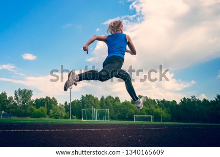 young fitness woman runner running on stadium track. The time of the jump in flight. Athletics. The concept of a healthy lifestyle and sports. Royalty-Free Stock Photo #1340165609