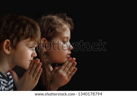 Little child folded his hand with praying in black background. Religion, prayer, faith and spirituality concept.