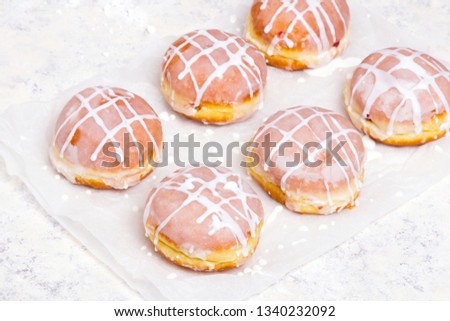 Traditional Polish donuts with white frosting on wooden background. Tasty doughnuts with jam. 