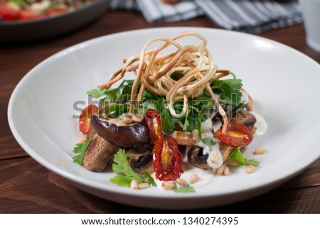 Grilled eggplant salad, tomatoes, mushrooms, cheese sauce, Cecil smoked cheese, fresh herbs. Wooden background