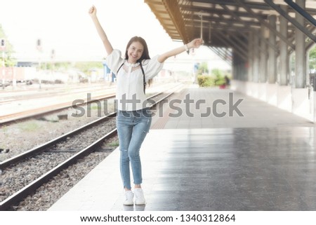 Asian traveler woman wait train at railway station.Travel holiday,relaxation concept.jump in happy feeling in free time or meet friend. 