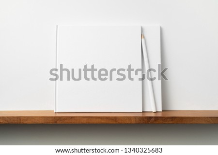 Design concept - front view of two square white notebook on bookshelf and white wall for mockup