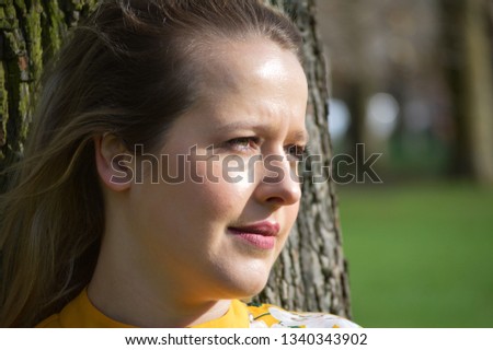 Blonde woman leaning on tree