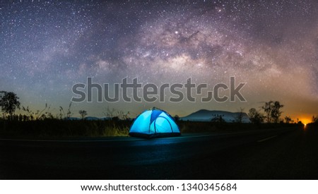 A blue tent in the dark night background is the milky way and many stars on the sky.