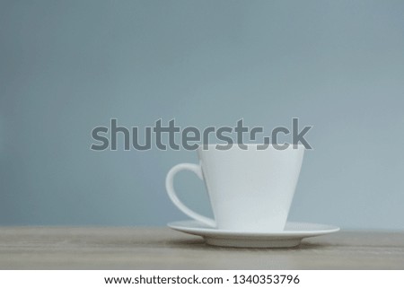 Splash in white cup of coffee on wooden table.