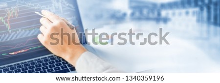 Woman hand with pen shows at graph on laptop. Computer screen with graphics of chart. Wide banner or panorama technology concept.