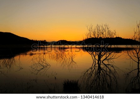 Landscape background. Sunset in the evening. The sunset behind the mountain The sky became golden The light of the setting sun is reflected in the water surface.