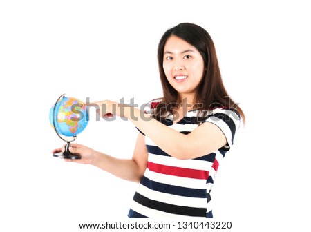 Happy young asian woman smiling while pointing at a world globe against a white background