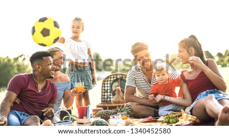 Happy multiracial families having fun together with kids at pic nic barbecue party - Multicultural joy and love concept with mixed people playing with children at park - Warm contrasted filter