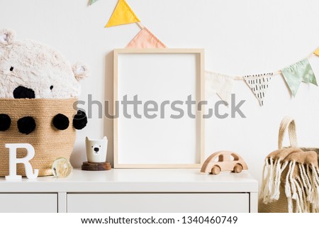 Stylish scandinavian nursery interior with  white teddy bear, wooden toys and cup. Hanging cotton flags. Natural basket on the white background wall. Cozy and sunny childroom. Real photo. Template.