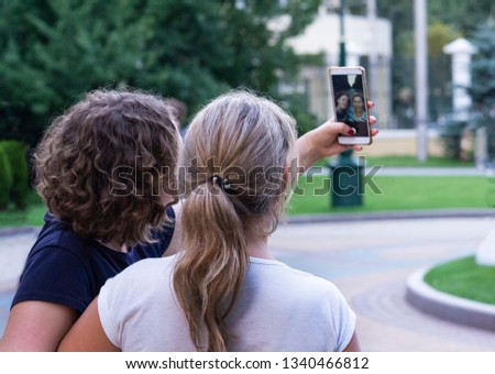 Two joyful cheerful girls taking a selfie while sitting together. Group of happy women  taking self-portrait.