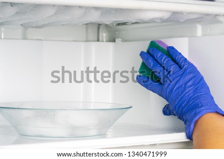 A cleaning lady washes the freezer. Cleaning the refrigerator. Royalty-Free Stock Photo #1340471999