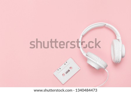 White cassette tape and headphones on a pink background. Party 90s concept.