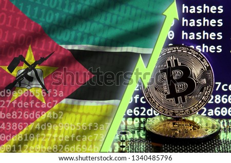 Mozambique flag and rising green arrow on bitcoin mining screen and two physical golden bitcoins