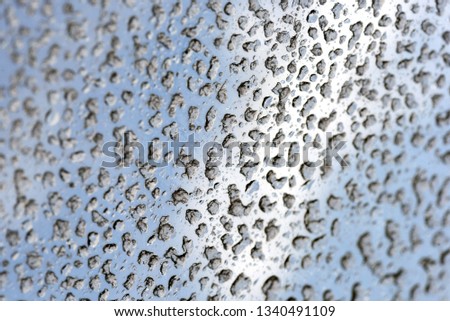 Fresh water rain drops and droplets on a clear glass window after a rainstorm creating an abstract pattern and rivulets of liquid