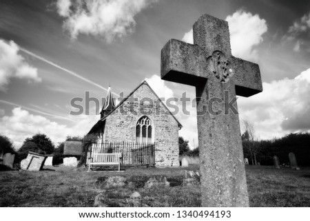 Single unmarked and worn gravestone in a churchyard with an old ancient church in the background with nobody