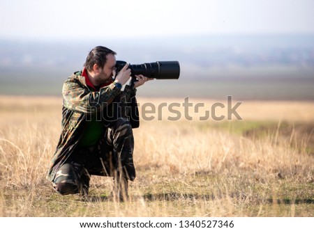 Wildlife, nature man photographer in camouflage outfit shooting,