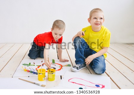 naughty creative children paint brush paints on paper funny colorful pictures on a wooden floor, art in a group art school. in a creative search for emotion