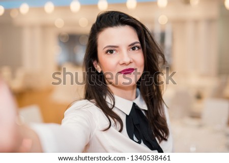 Young woman taking selfie on blur background with light bokeh of dinning place. white shirt