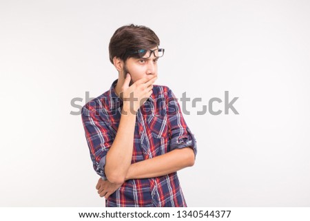 People, emotions and gesture concept - young surprised man covering his mouth with his hand on white background with copy space