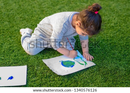 Portrait of the cute little girl drawing a picture of earth globe.