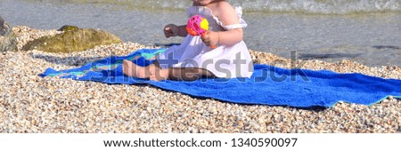 Girl sitting sitting on the sea holding a rattle summer bright colors