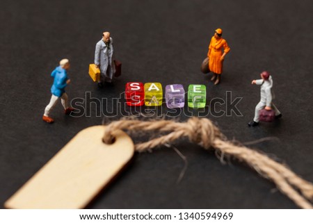 Discount sale concept. Miniature people with the label for clothes. Close up. 