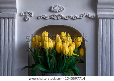 yellow flowers tulips by the white fireplace