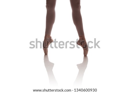 The legs of a ballerina in beige pointe doing poses on a white background